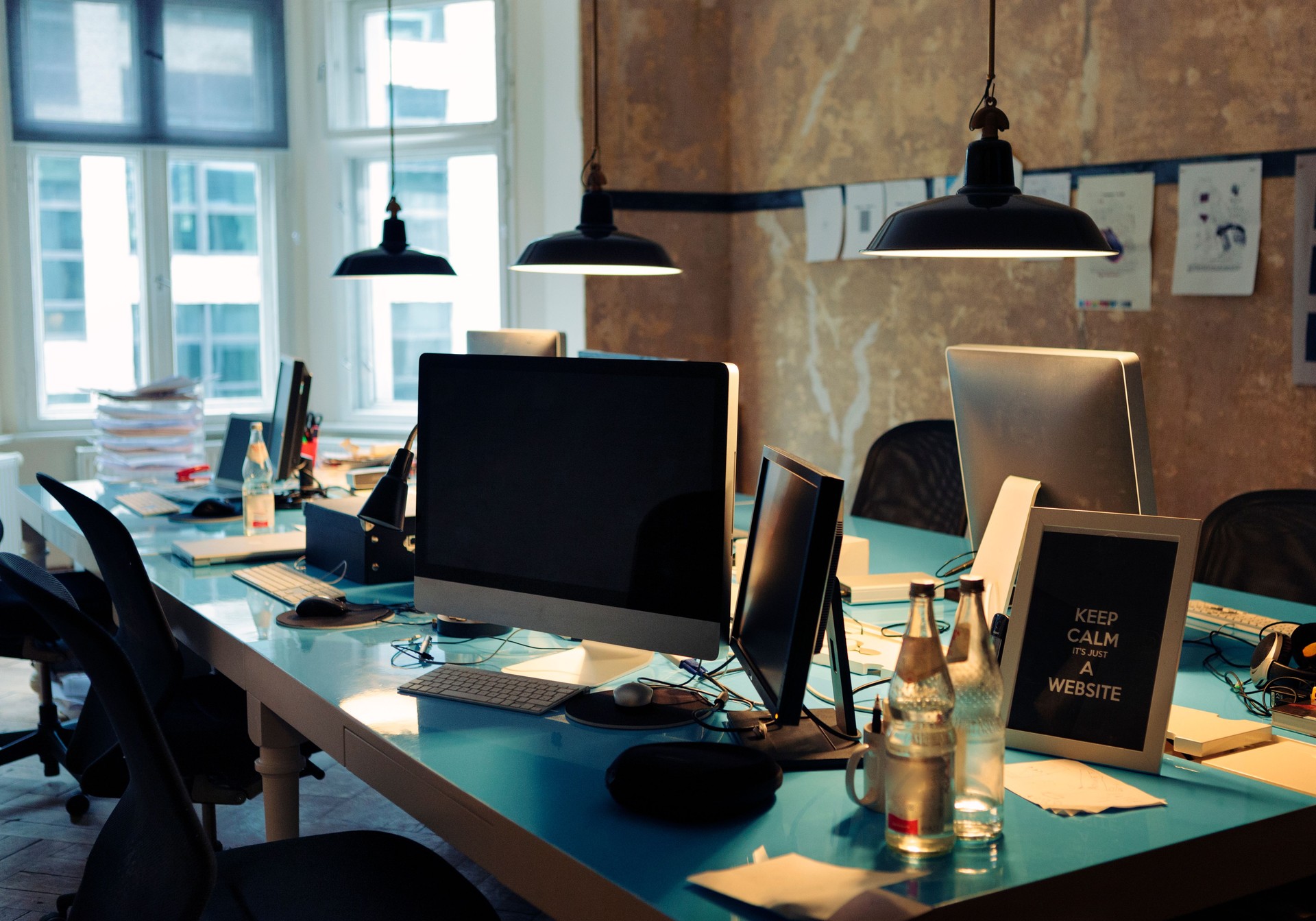 Long blue table covered in computers and papers